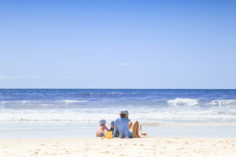 An adult and children enjoying time together on a sunny beach